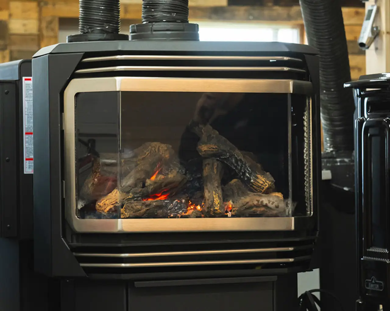Black fireplace stove with glowing logs in a showroom.