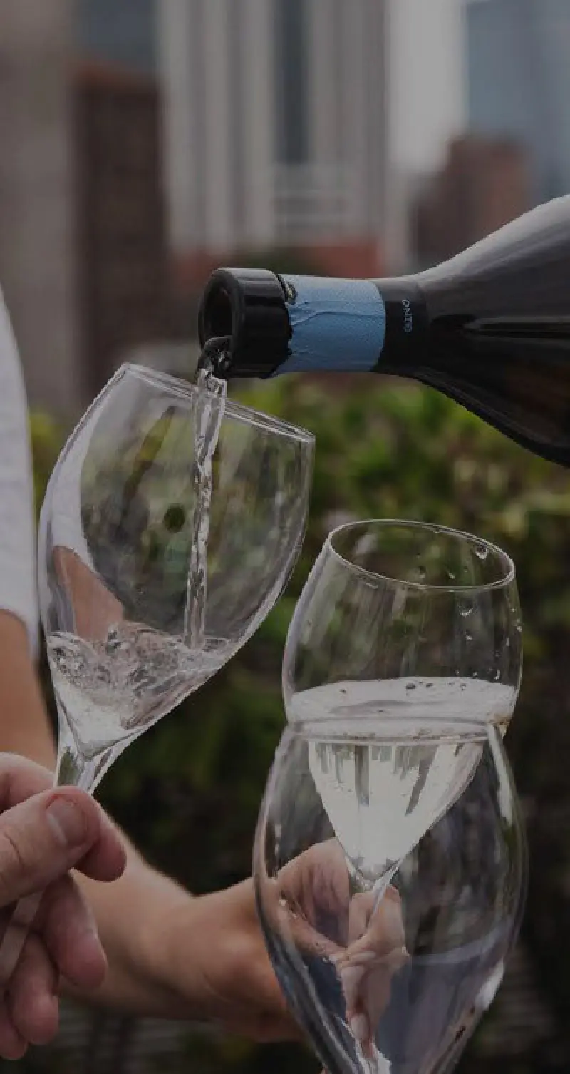pouring sparkling wine into two glasses outdoors