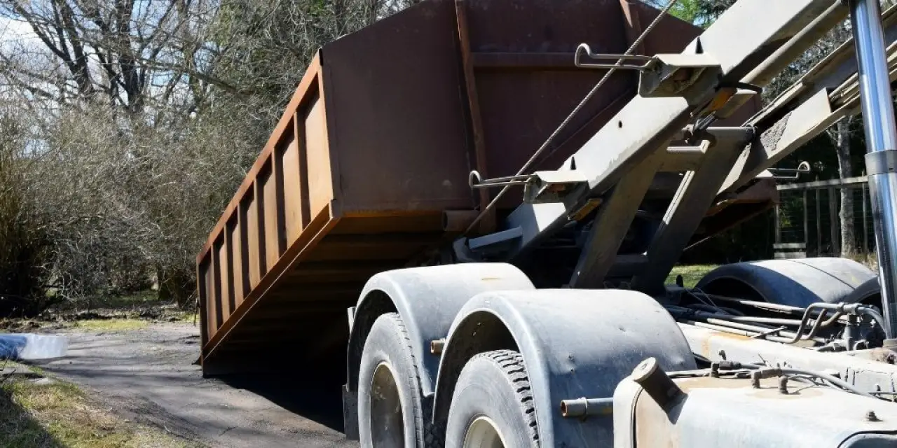 dump truck unloading a dumpster