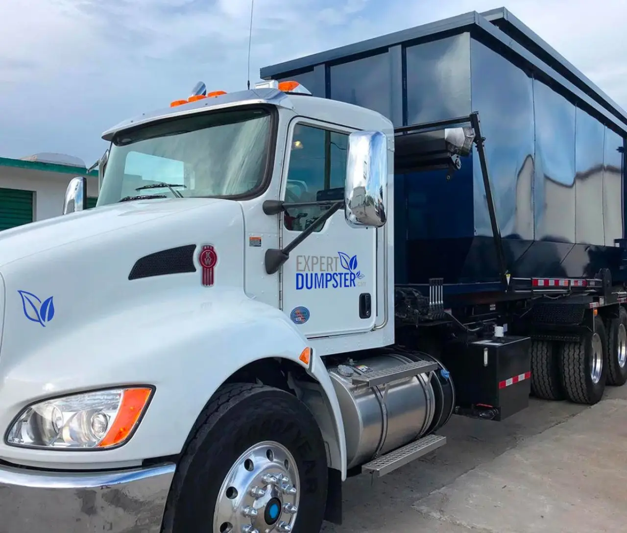 white truck with Expert Dumpster logo hauling a large blue dumpster