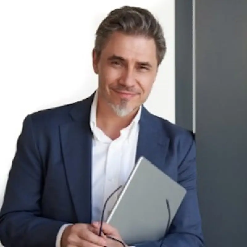 man in a blue jacket holding a grey folder and glassess after cataract surgery