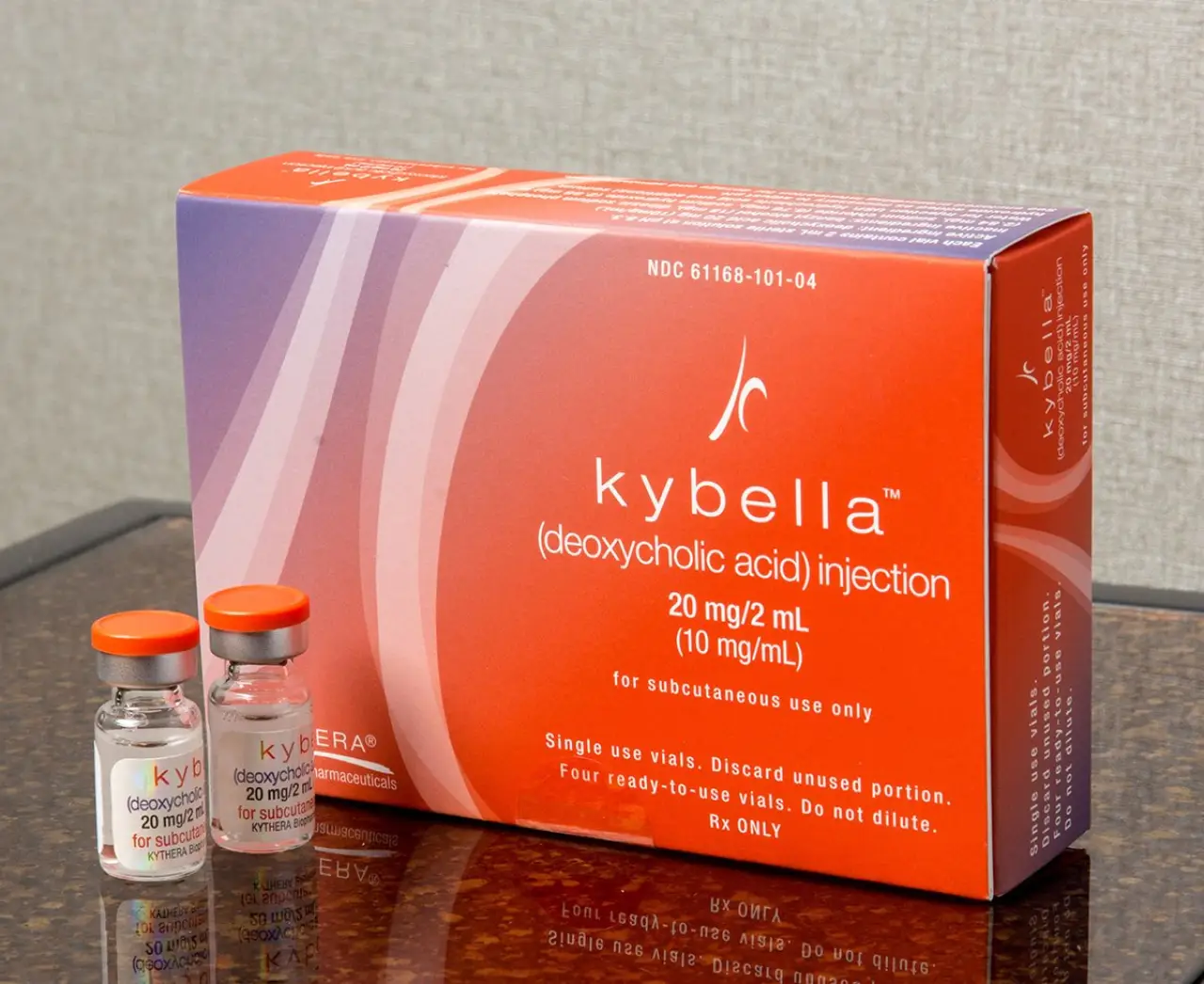 A box of Kybella injection with two vials placed beside it on a countertop.