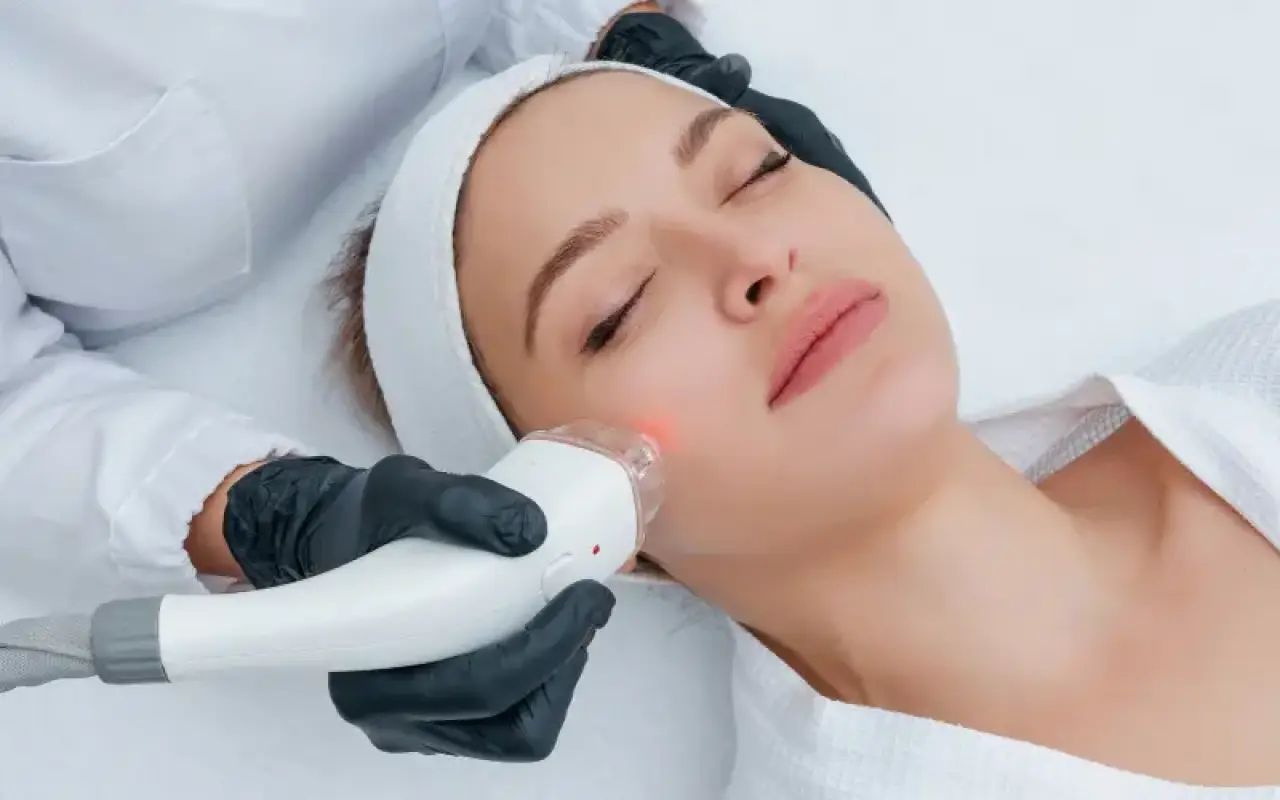 Woman receiving a facial treatment with a handheld device