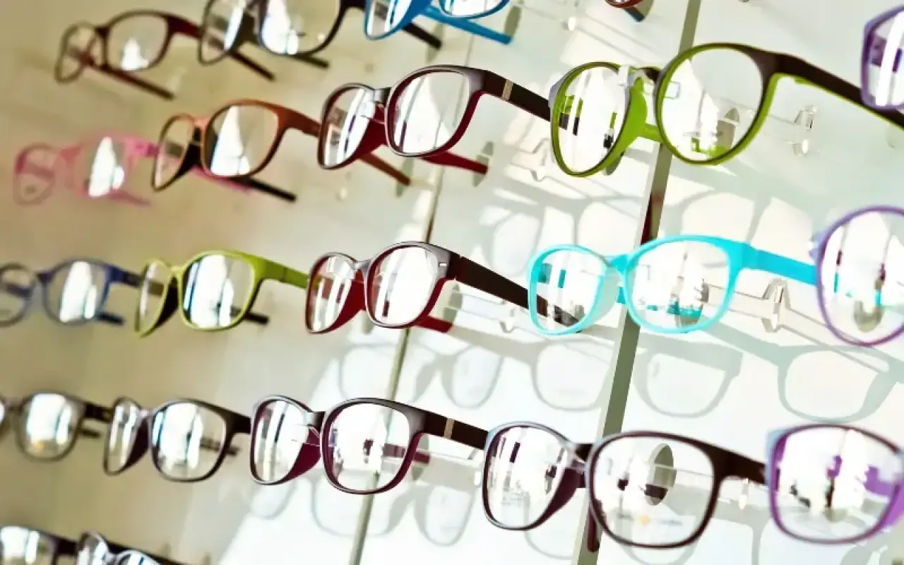 Person selecting eyeglasses from a display of frames in an optical store