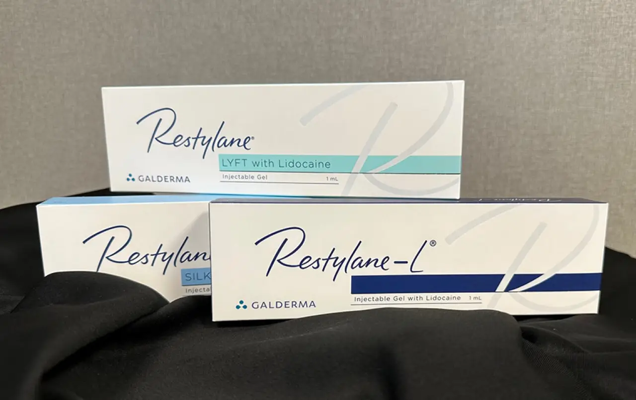 Three boxes of Restylane injectable gels with lidocaine stacked on a black cloth.