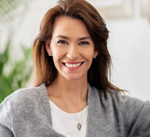 Smiling woman with brown hair wearing a gray sweater