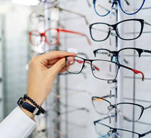Person selecting eyeglasses from a display of frames in an optical store