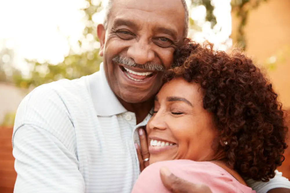 A man and a woman hugging each other and smiling.