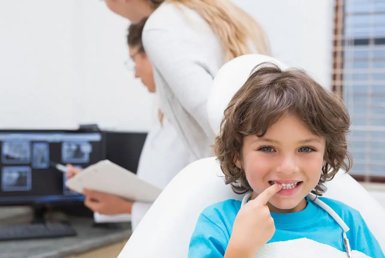 small child at dentist pointing at teeth