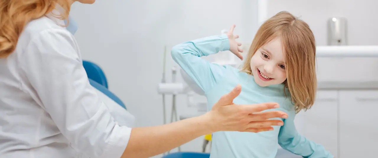 Dentist slapping hands with a young patient.