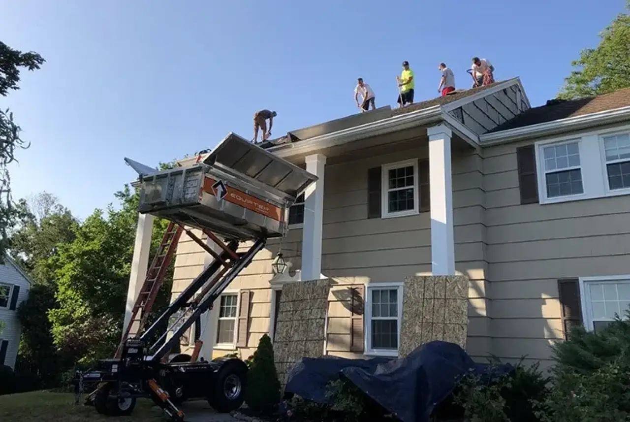 men working to replace roof on a two story home with tan siding