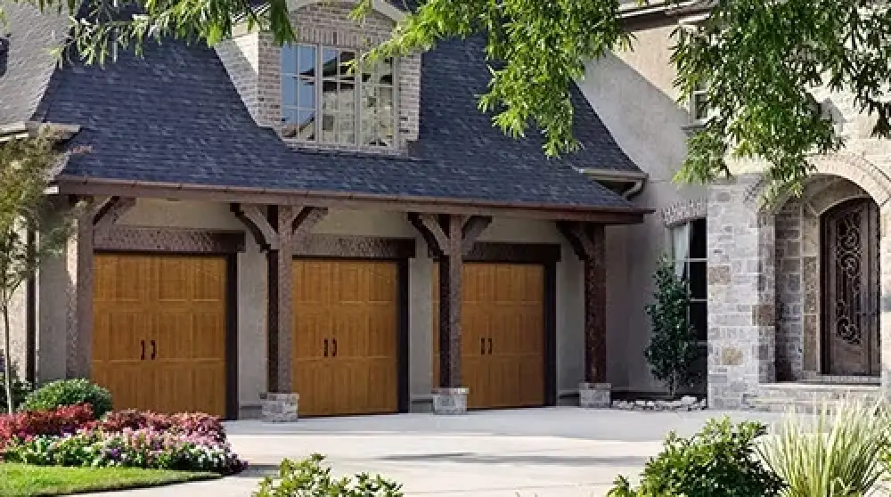 gorgeous home with three garage doors and stone column at entry door