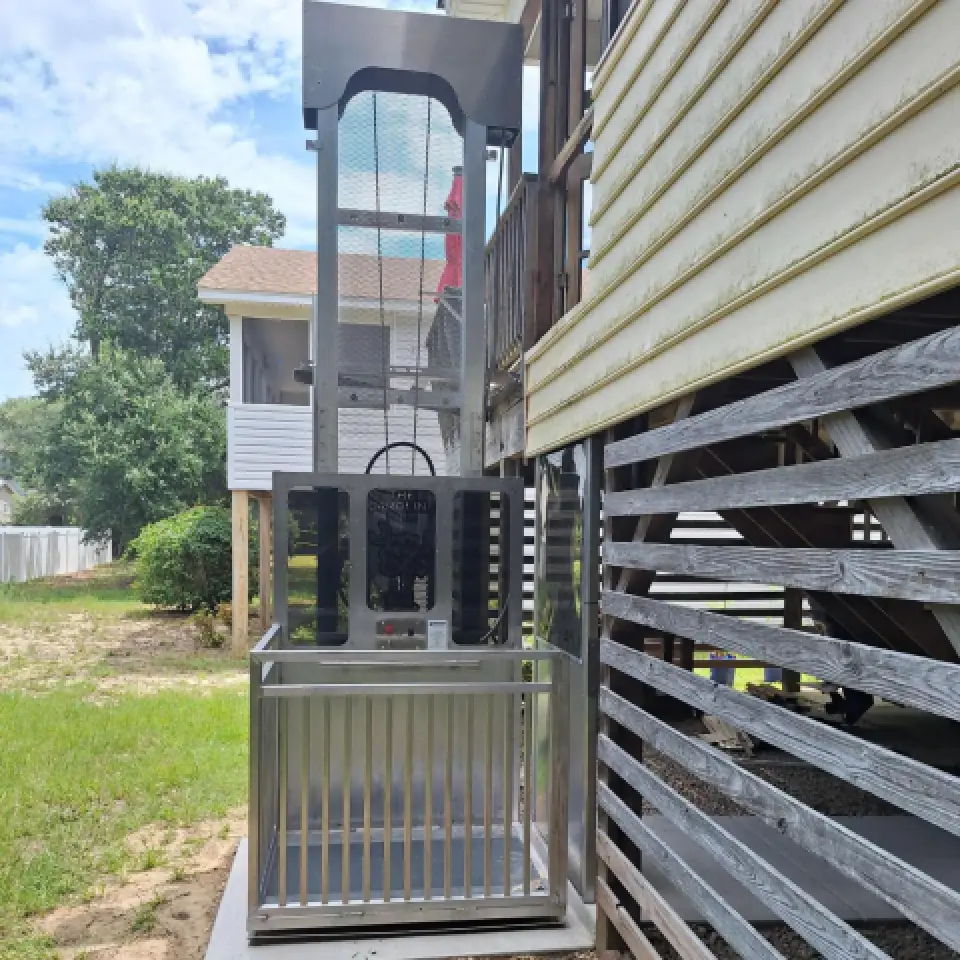 Outdoor residential wheelchair lift next to a house, with metal railing and platform.