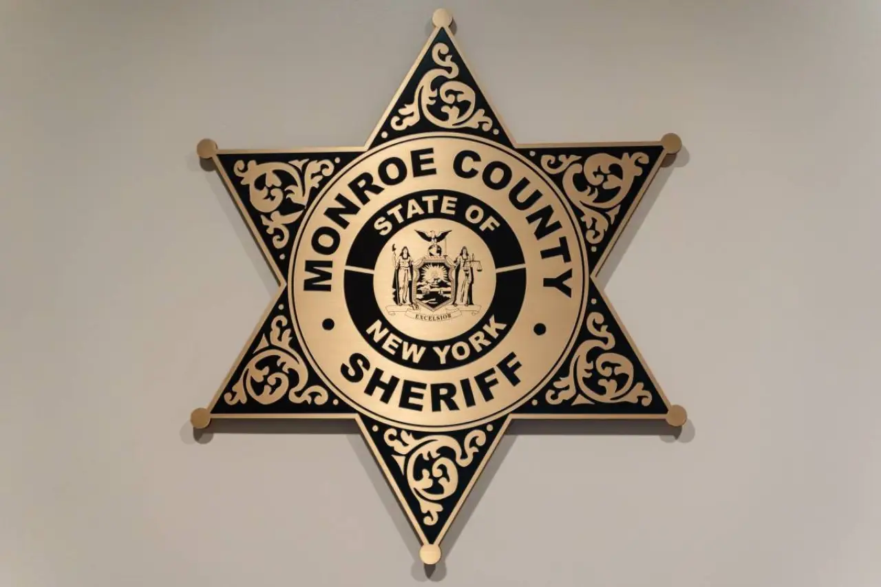a black dog interacts with a sheriff and a woman at the Monroe County Sheriffs office
