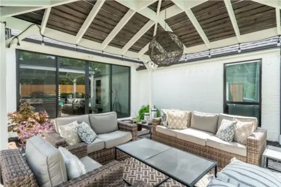 covered patio with wicker furniture, throw pillows, glass table, and modern pendant light