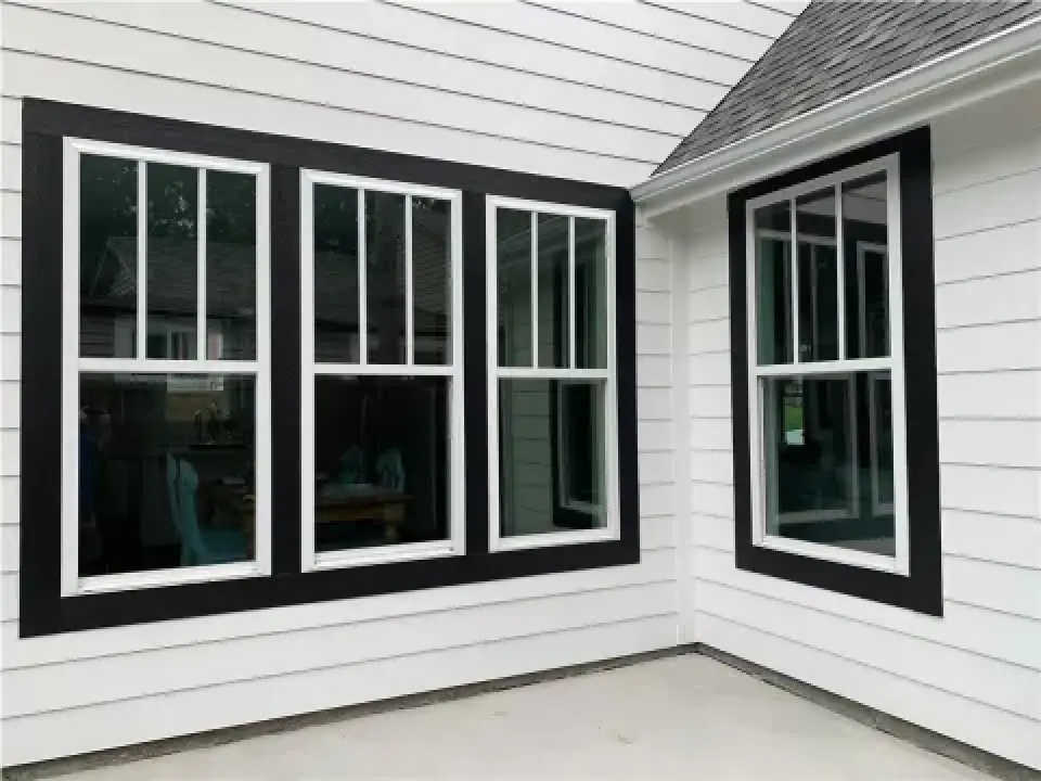 white house exterior with three large black-trimmed windows and one black-trimmed corner window
