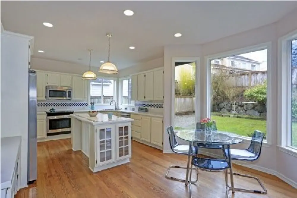 Bright kitchen dining area with large windows overlooking the backyard.