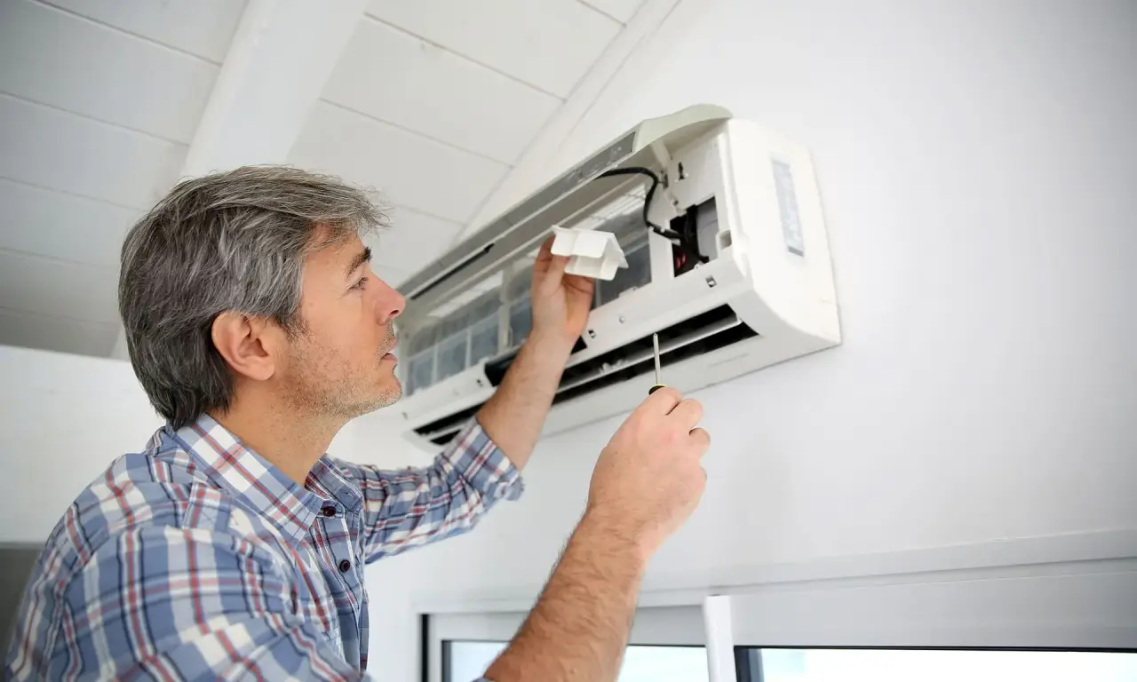 Technician servicing a wall-mounted air conditioning unit.