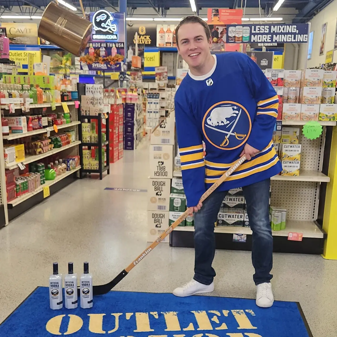 young man in hockey jersey posing with a hockey stick near bottles in liquor store