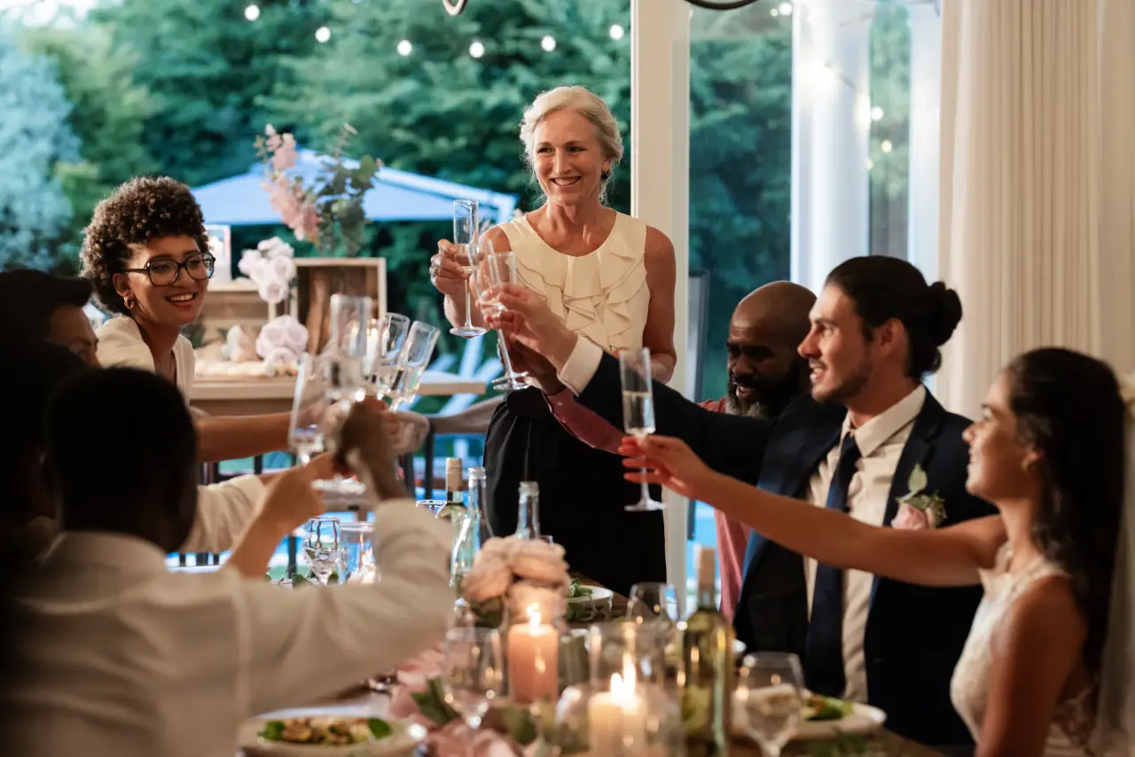 Guests raising champagne glasses in a toast at a wedding reception.