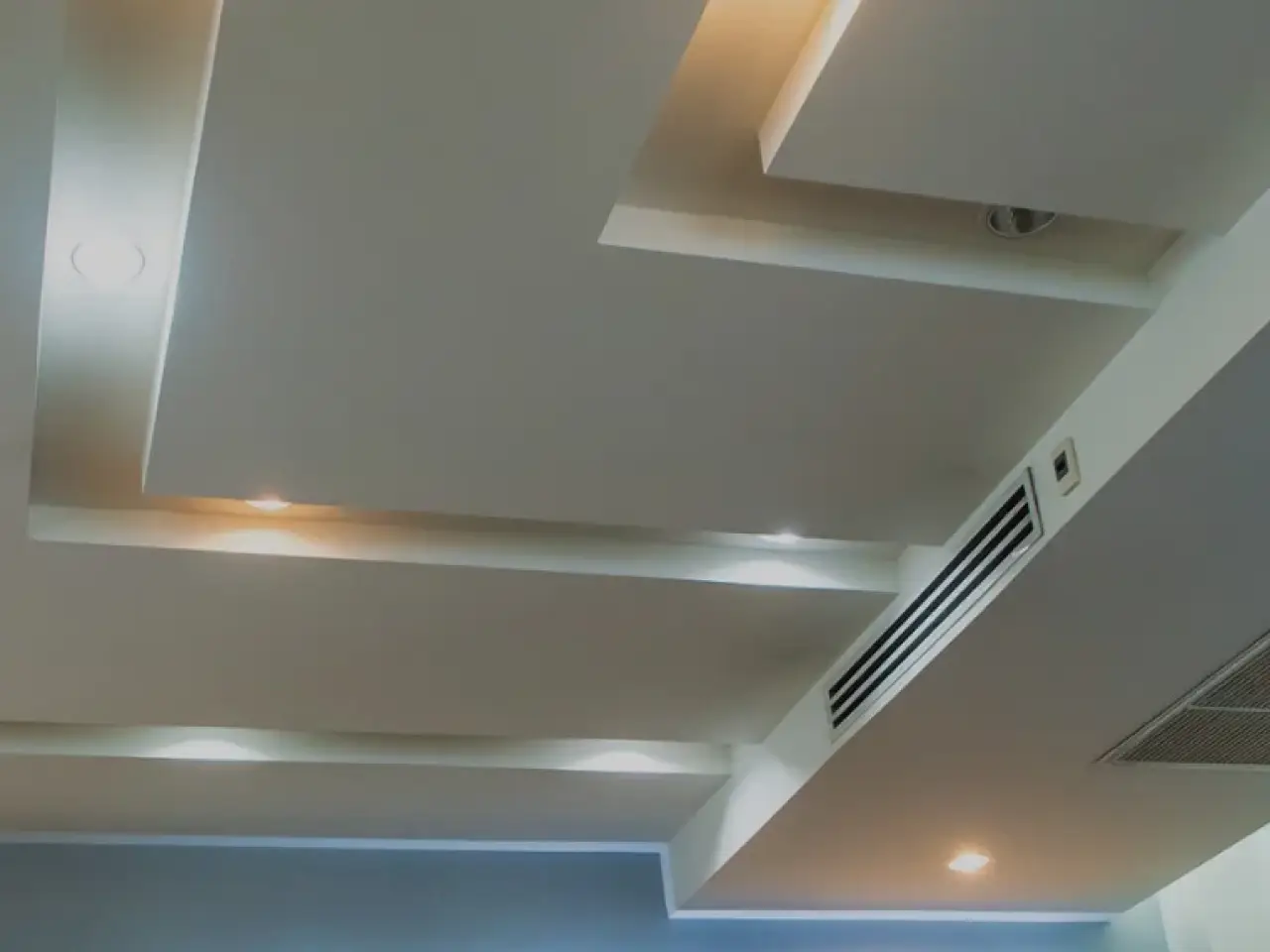 Recessed ceiling lights and ventilation grilles in a modern interior.