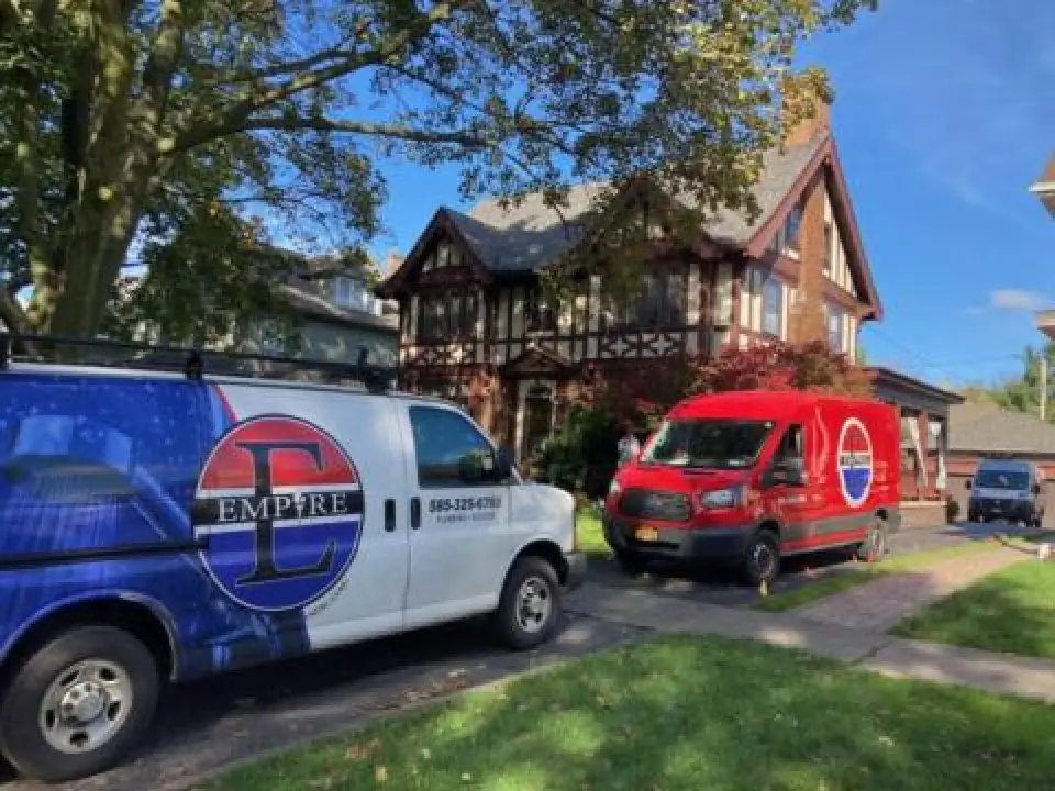 One blue and white van and a red van in the driveway of a house. 