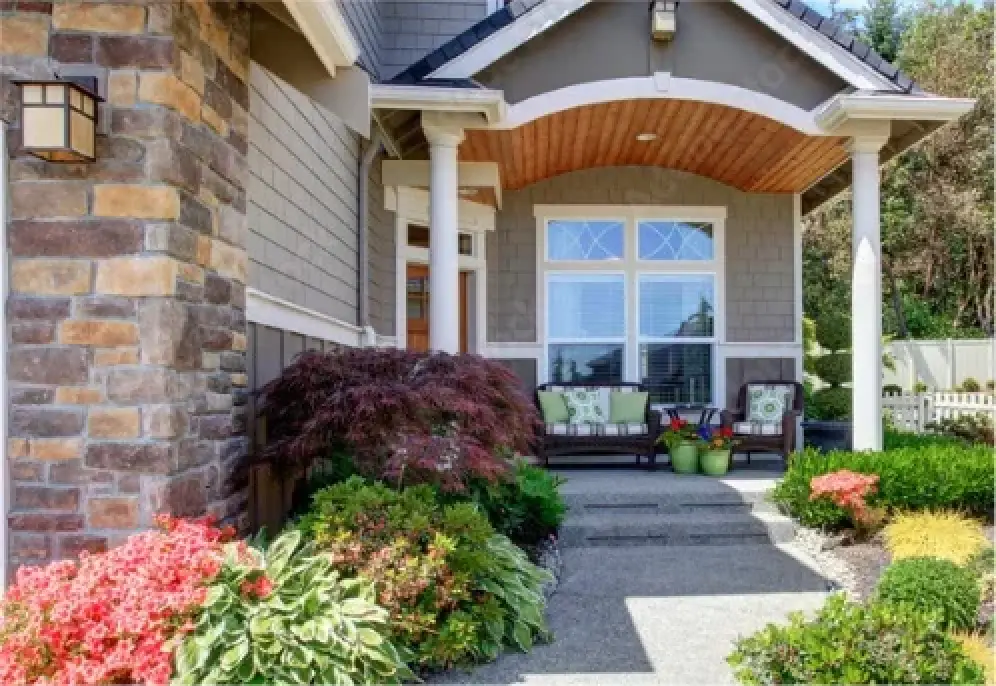 Well-maintained building entrance with stone siding, porch, and landscaped walkway.