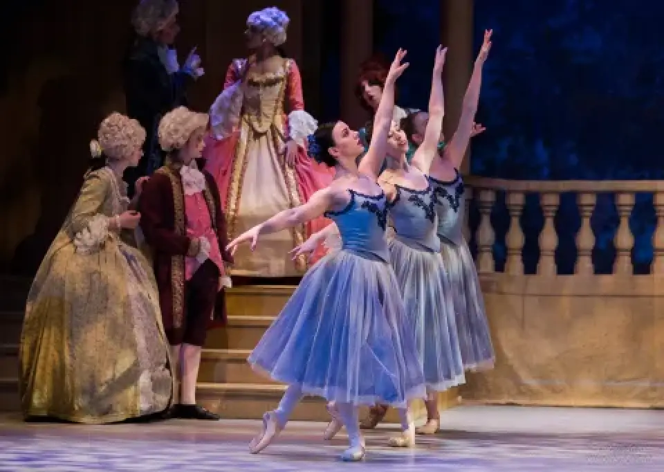 Two Cinderella dancers in blue tutus perform as courtiers watch.