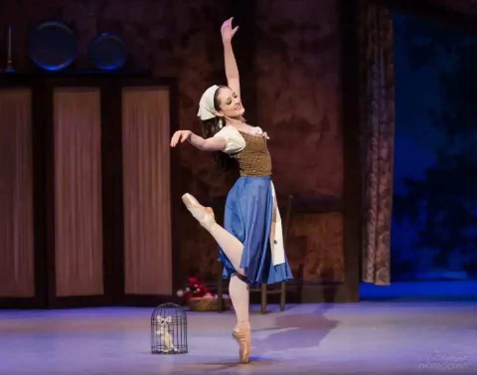Cinderella dancer poses en pointe on a staged kitchen set.