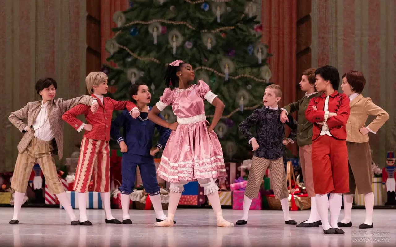 Children performing The Nutcracker onstage in front of a Christmas tree.