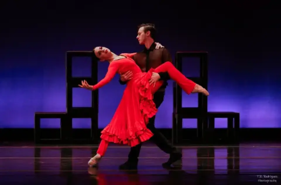 Dancers performing Carmen onstage, with the ballerina in a red dress.