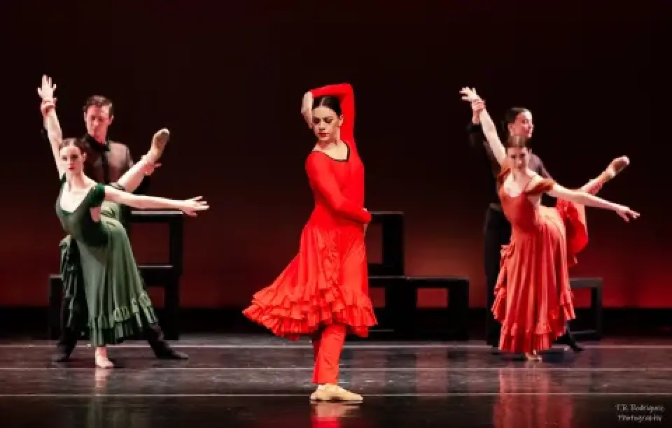 Dancers perform Carmen onstage in red and green costumes.