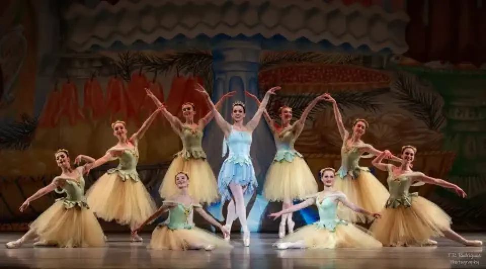 Ballet dancers pose onstage in pastel costumes for The Nutcracker.