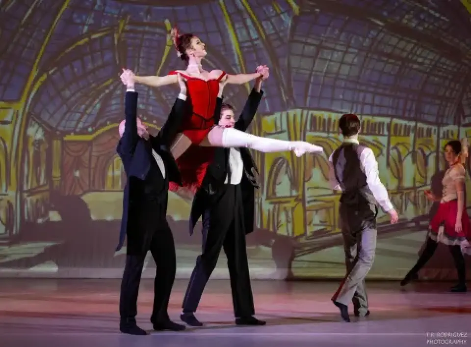 Ballerina in red lifted by dancers during Moulin d'Paris performance.