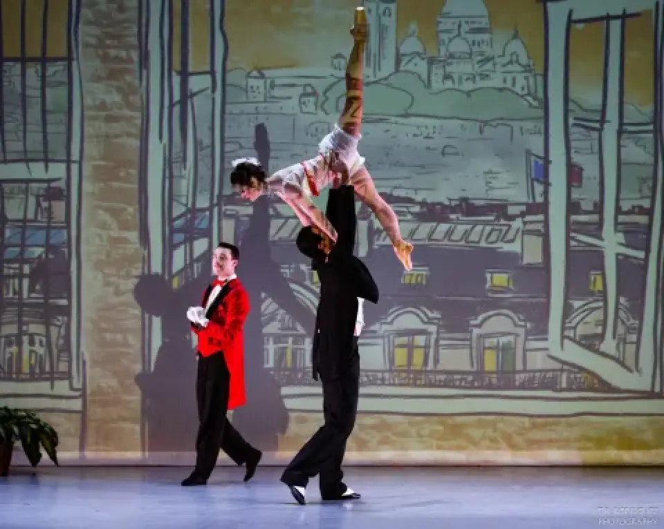 Dancer lifted overhead during Moulin d'Paris ballet performance.