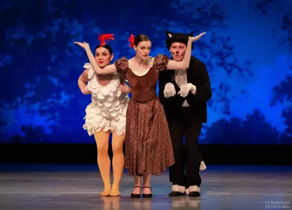 Three Ugly Duckling dancers pose onstage against a blue backdrop.