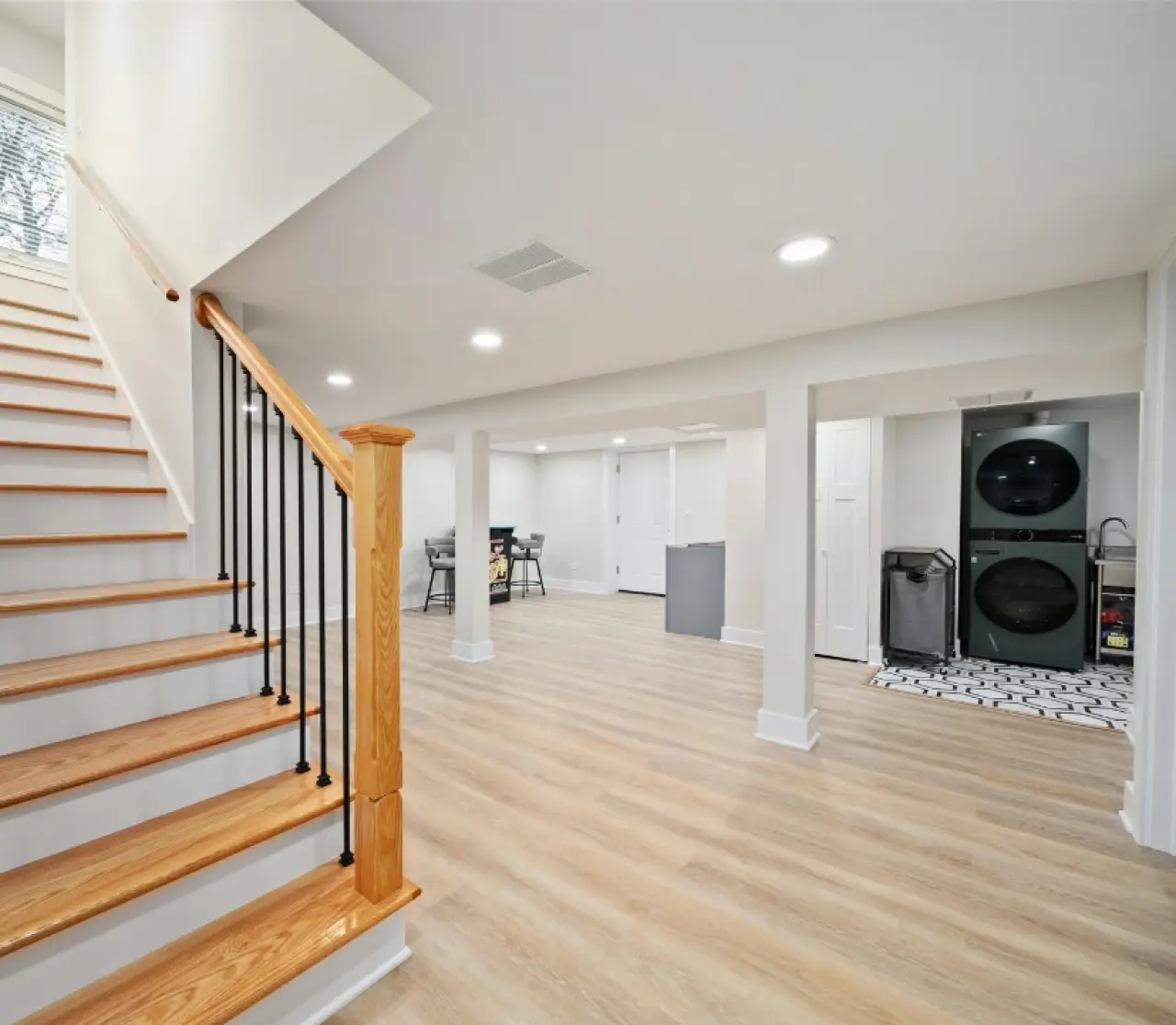 Finished basement with wood flooring, laundry, and open area featuring recessed lights.