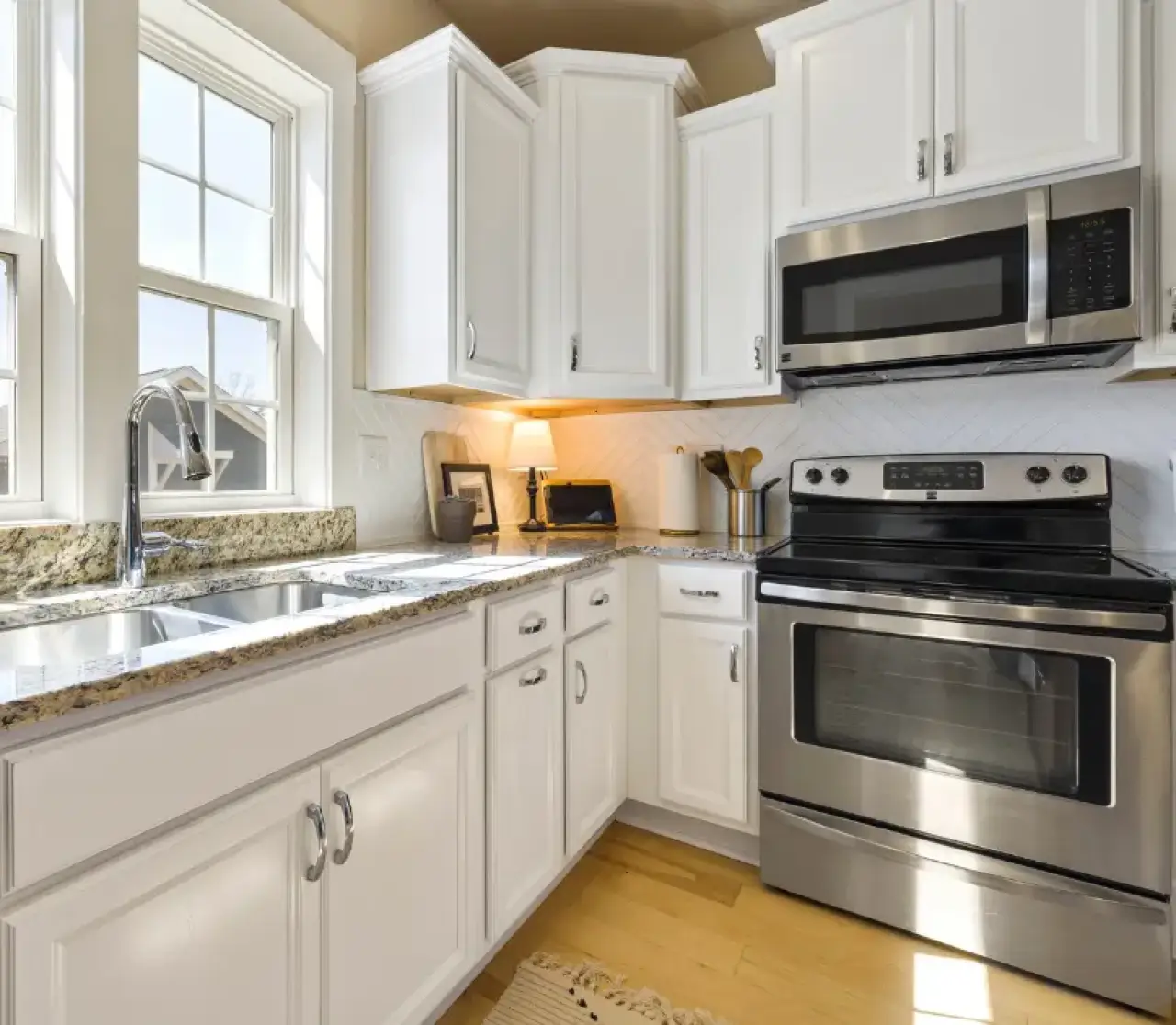 Bright kitchen with white cabinets, granite countertops, and stainless steel appliances.