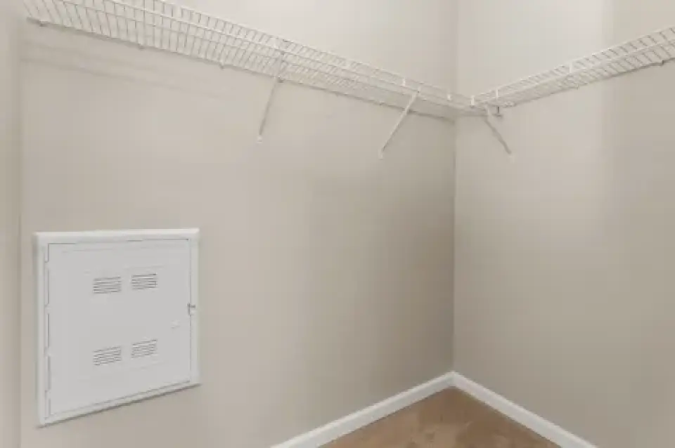Walk-in closet with wire shelving and utility access panel.