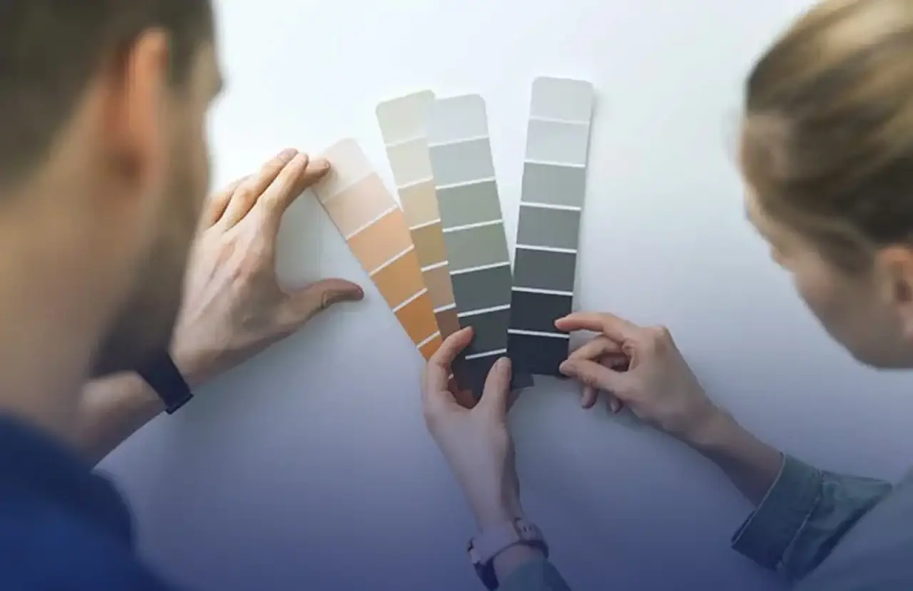 Homeowners comparing exterior paint color swatches for a house update.