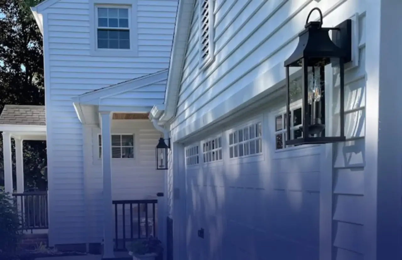 White home exterior with painted siding, garage doors, and black lanterns.
