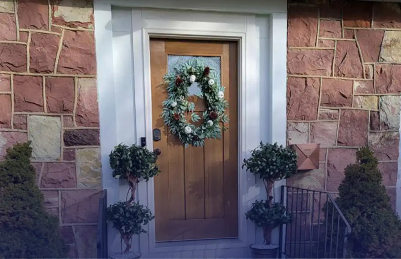 Wood front door with freshly painted white trim and stone siding.