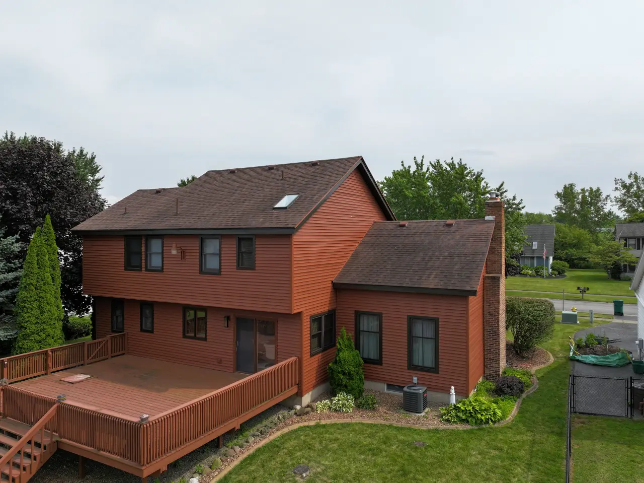 A house with a brown roof, brown siding and a big back deck.