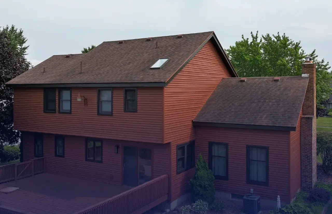A brown house with new roofing and siding.