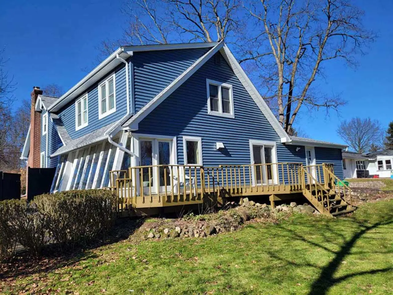 Blue house with a porch and a green lawn.