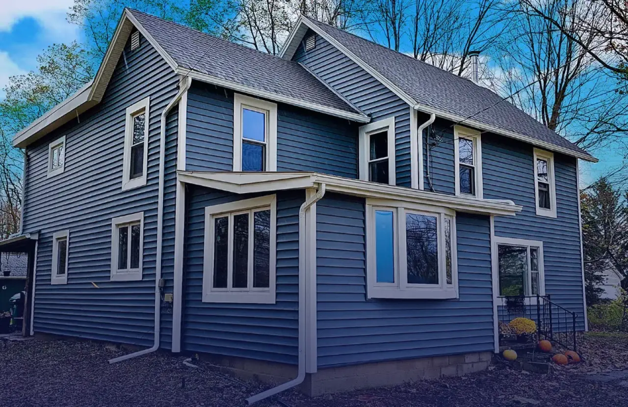 Blue house with new siding and pumpkins on the front porch.