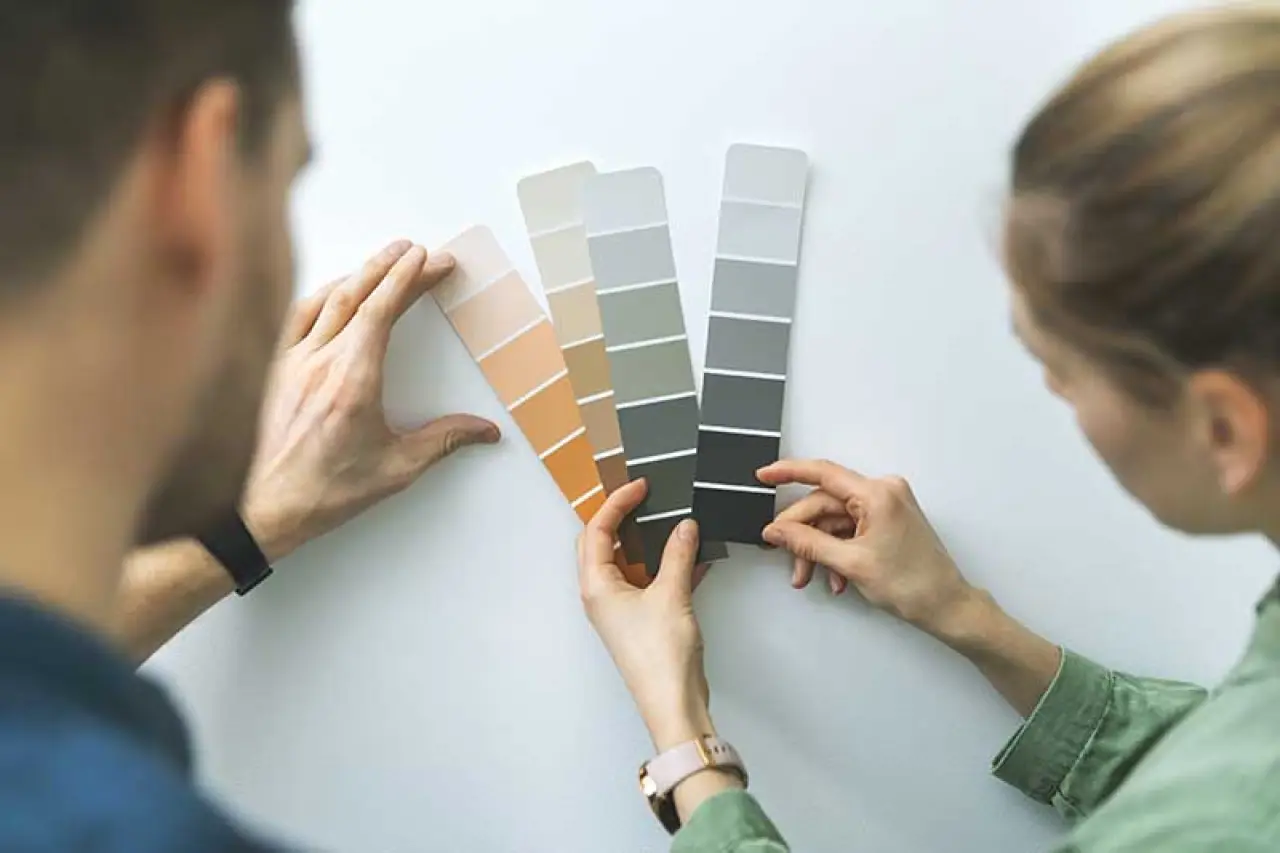 Two people comparing paints strips from Sherwin Williams.