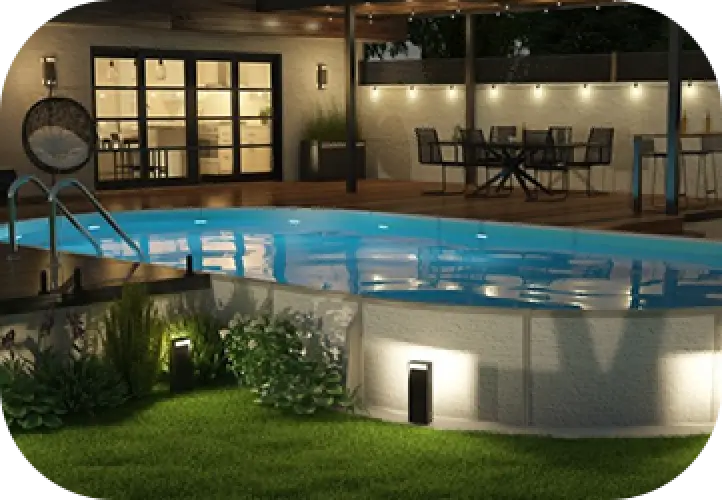 Illuminated backyard pool and patio area with outdoor dining set and lush green grass at night.