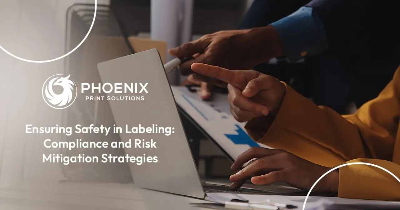 Two people review documents at a desk with Phoenix Print Solutions and safety labeling text.
