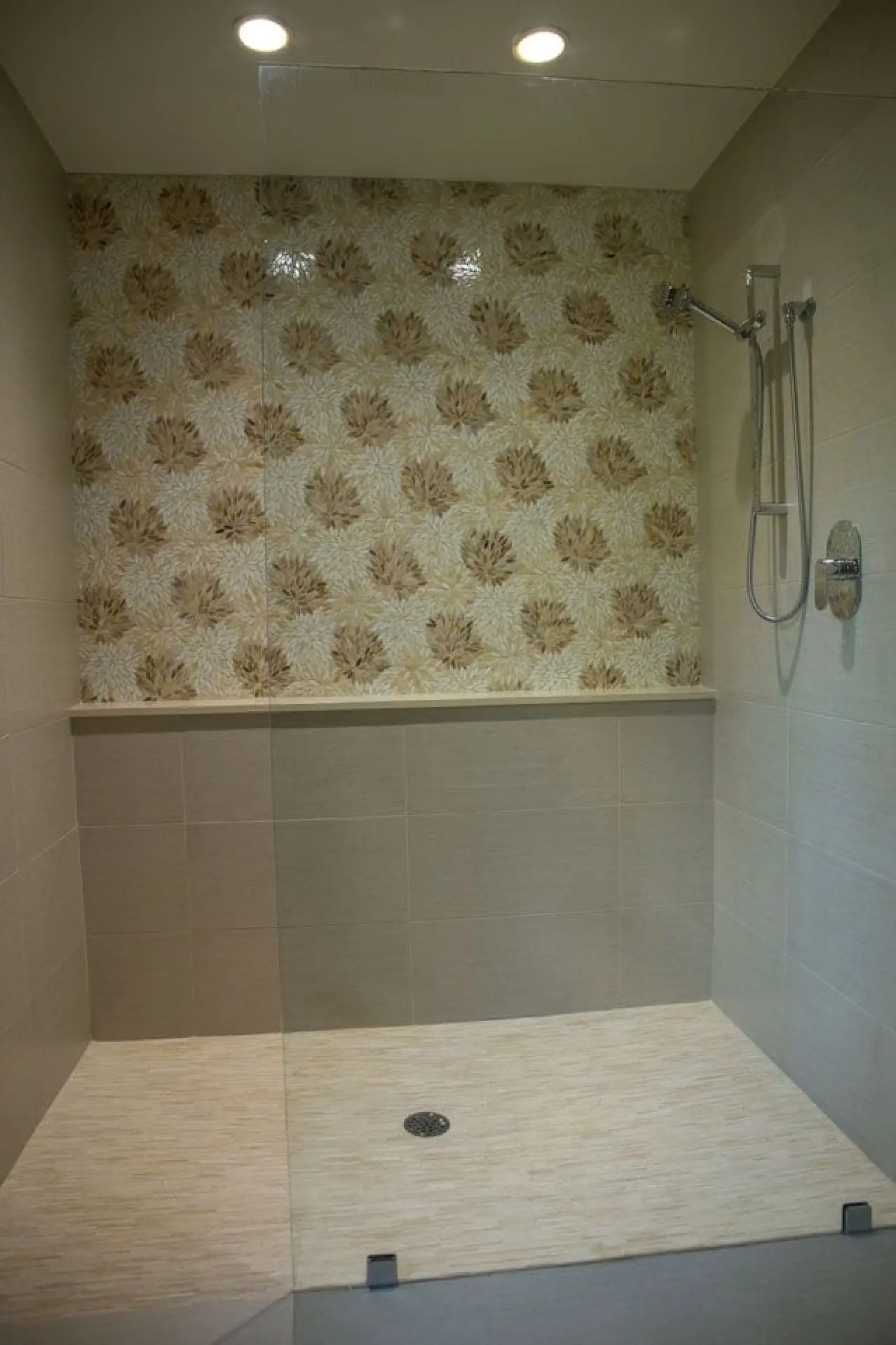 shower with artistic tile, glass door and cream tile flooring